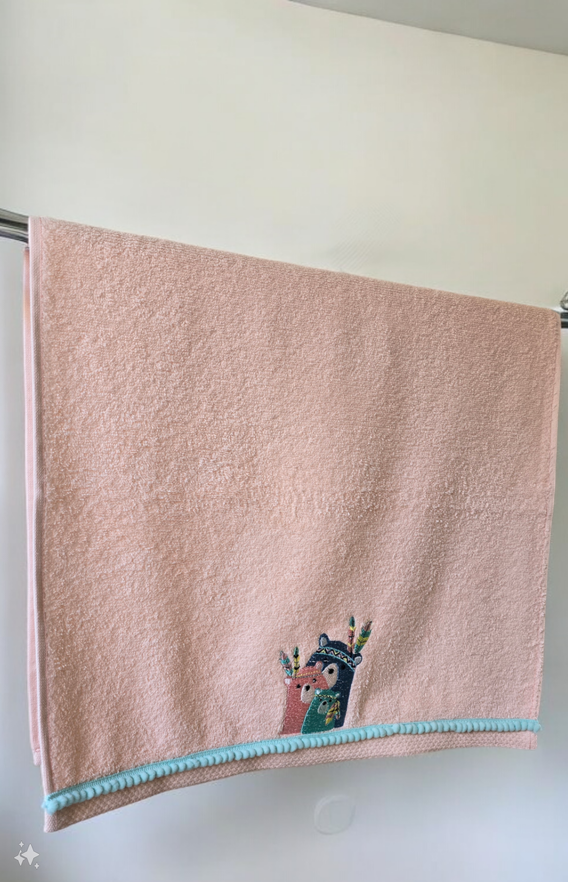Pink towel with cartoon character and blue trim hanging on a rack.